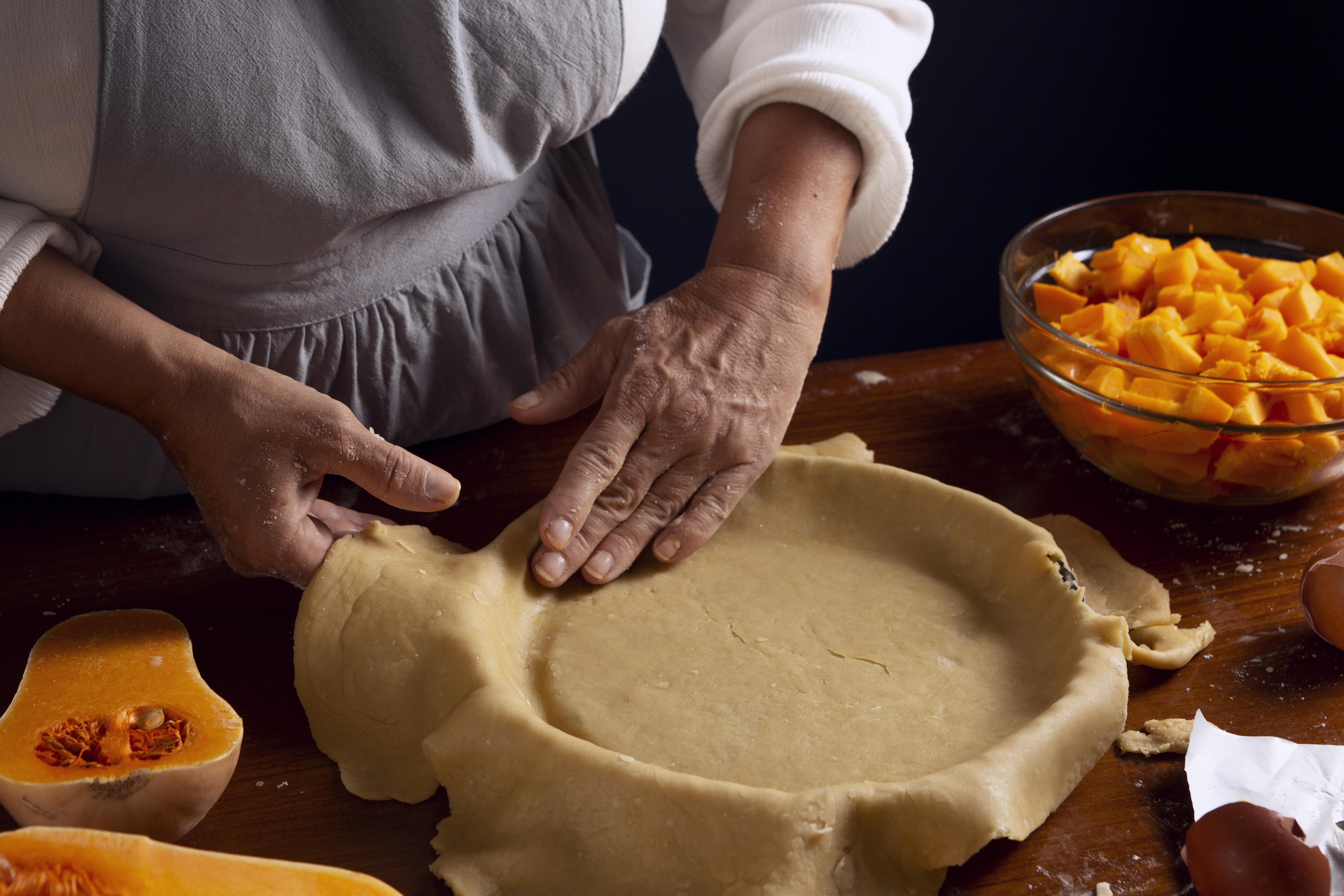 Una masa de tarta siendo colocada en una asadera.